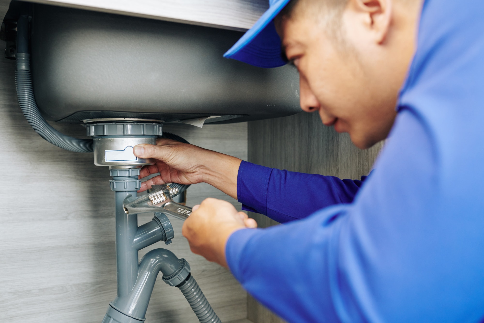 Technician repairing a leaking sink trap, a common snagging defect in new properties